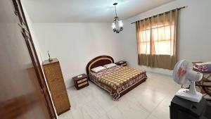 a bedroom with a bed and a window with a fan at Pousada Casa da Vó Dita in Ouro Fino