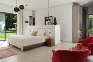 a bedroom with a white bed and red chairs at Villa Netumia in Marrakesh +76 photos