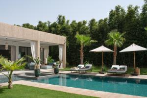 a swimming pool with lounge chairs and umbrellas at Villa Netumia in Marrakesh