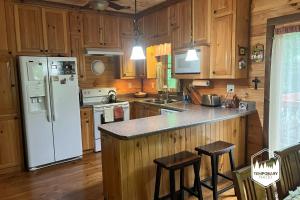 a kitchen with a white refrigerator and wooden cabinets at Tree Top Hideaway - Private with Games Firepit More in Blue Ridge