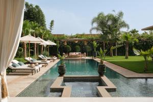 a swimming pool in a backyard with chairs and umbrellas at Villa Netumia in Marrakesh