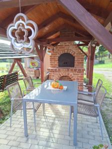 a blue table and chairs in front of a brick oven at Erdőszéli Apartman in Szőce