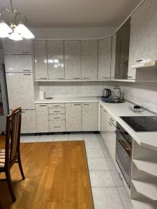 a kitchen with white cabinets and a wooden floor at Royal Apartment in Banja Luka +5 photos