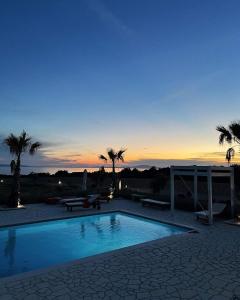 a swimming pool with palm trees and a sunset at Villa Melody Novalja in Novalja