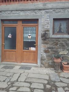 una porta in legno di un edificio in pietra con piante in vaso di Agriturismo La Buca a Cutigliano