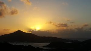 einen Sonnenuntergang über einem Hügel mit einem Kreuz oben in der Unterkunft Sunset Gardens Guesthouse in Charlotte Amalie