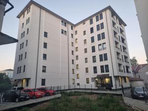 a large white building with cars parked in a parking lot at ZARA Apartman in Bijeljina