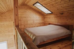 a small bedroom with a bed in a wooden cabin at Ambro Krasts in Maskava