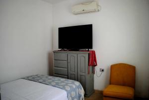 a bedroom with a tv on a dresser and a chair at Suinda casa de campo in Corrientes +2 photos