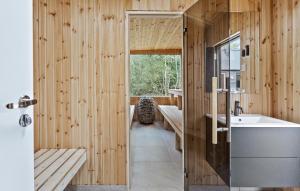 a bathroom with a sink and a wooden wall at Lovely Home In Væggerløse With Sauna in Marielyst +18 photos