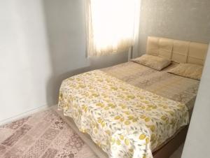 een slaapkamer met een bed met een geel dekbed en een raam bij Egepar Rezidance Apart otel in Buca