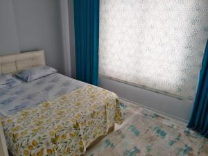 een slaapkamer met een bed en een raam met blauwe gordijnen bij Egepar Rezidance Apart otel in Buca