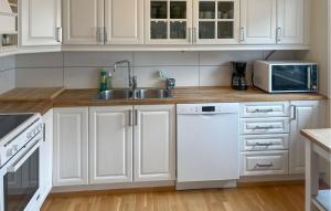 una cucina con mobili bianchi, un lavello e un microonde di Stunning Apartment In Kristiansand S a Kristiansand