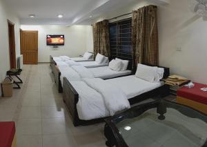 a row of beds in a room with a tv at Haven Lodge Bhurban - Deluxe Rooms with Mountain View in Murree