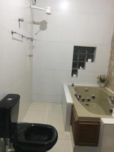 a bathroom with a toilet and a sink and a tub at Zaffir Apartamento in Várzea Grande