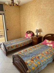 a bedroom with two beds and a table with a lamp at Appartement Belevédère in Casablanca
