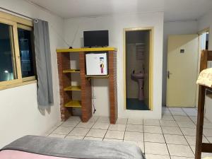 a room with a bathroom with a toilet and a tv at Pousada Pimenta in Torres