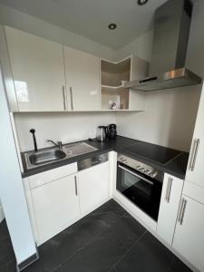 Una pequeña cocina con gabinetes blancos y un fregadero. en Pension Zur Linde, en Geisfeld 9 fotos más