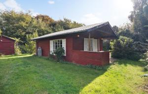 a small red house on a grass field at Holiday Home Strandvej F in Eskebjerg +11 photos