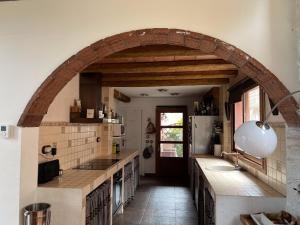 a kitchen with an archway with a sink and a refrigerator at Cal Fraguerau in Ulldemolins