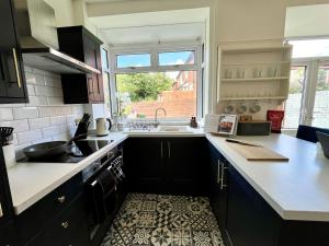 a kitchen with black cabinets and a sink and a window at Stylish 3-bed home in Prestwich with free parking in Manchester