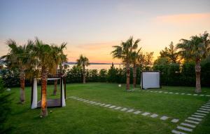 a garden with palm trees and a table and a screen at Villa Anastazia in Starigrad +35 photos