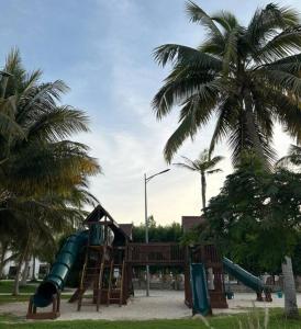 une aire de jeux avec des toboggans et des palmiers dans un parc dans l'établissement Hawana Salalah Resort - SL 2, à Salalah