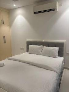 une chambre avec un grand lit avec des draps et des oreillers blancs dans l'établissement Hawana Salalah Resort - SL 2, à Salalah