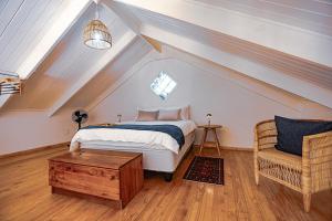 a attic bedroom with a bed and a chair at Bamboo Cottage in Riebeek-Kasteel
