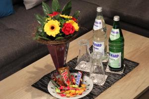 a vase with flowers and drinks on a table at Apartment Haus Sternenhimmel in Lehmrade