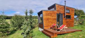 a tiny house with two chairs on a deck at Tiny House Pod Třešní in Kaznějov