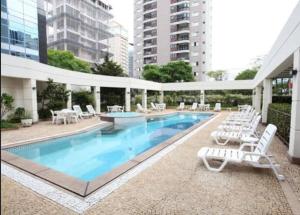 a swimming pool with white lounge chairs and a building at TW Cyclinn Vila Olimpia in São Paulo