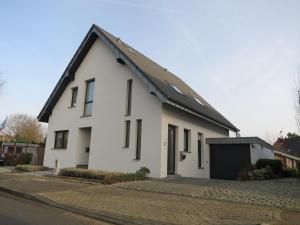 a white house with a black roof on a street at Ferienwohnung Mauritiusstraße in Xanten