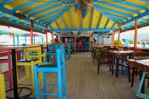 um restaurante com cadeiras e mesas coloridas e um telhado em Graham's Place em Guanaja
