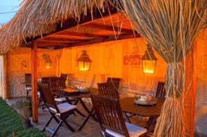 a patio with a table and chairs under a thatch roof at ZEVKLİLER ALAÇATI hotel in Alaçatı