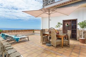 un patio avec une table et un parasol dans l'établissement Amazing Country House with Ocean View, Cueva de la Arena, à Garachico