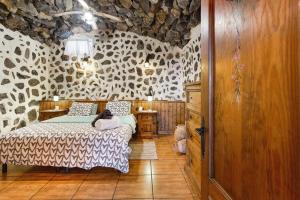 une chambre avec un lit et un mur en pierre dans l'établissement Amazing Country House with Ocean View, Cueva de la Arena, à Garachico
