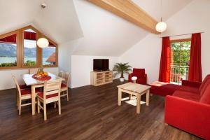 ein Wohnzimmer mit einem roten Sofa und einem Tisch in der Unterkunft Seehotel und Appartements Schnöller in Rieden
