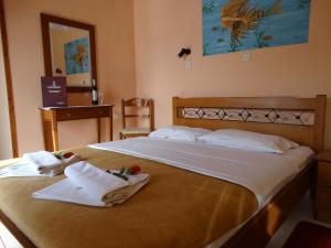 1 dormitorio con 2 camas, toallas y espejo en Akrotainaritis Rooms, en Yerolimin