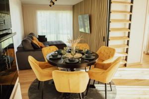 a dining room with a black table and yellow chairs at Dzintaru māja in Ģipka