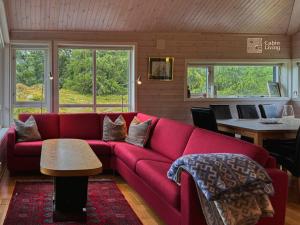 a living room with a red couch and a table at Cabin at Sjusjøen Birkebeiner trail ski in out, 8 beds, 2 bathrooms & Wifi in Sjusjøen +21 photos