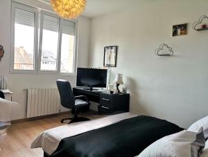 a bedroom with a bed and a desk with a computer at Appartement moderne à Elbeuf in Elbeuf