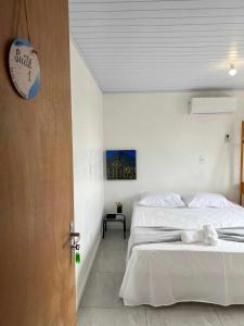 a white bedroom with a bed and a door at Suíte com AR BWC Privativo poucos metros da Vila Germânica Oktoberfest in Blumenau
