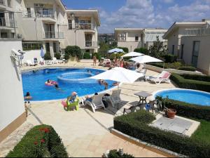 a swimming pool with people sitting in chairs and umbrellas at Sunny Villa in Byala