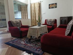 a living room with two red chairs and a table at Areca Holiday Apartment in Siliguri