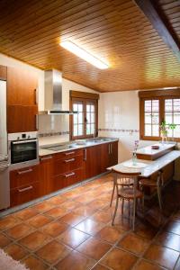 Una cocina grande con gabinetes de madera y una mesa. en Villa Laudina, en Vilaboa