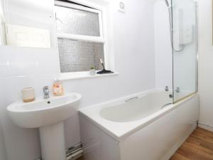 a white bathroom with a sink and a bath tub at 60B Castlegate in Berwick-Upon-Tweed +10 photos