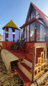 een klein huis met 2 stoelen en een veranda bij Titicaca Alpina HARMONY lodge in Puno