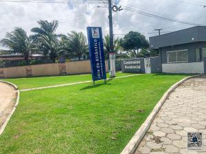 a sign in the grass in front of a building at Casa temporada na praia Joia do Atlântico - Ilhéus - Ba in Ilhéus
