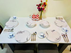 a white table with plates and utensils on it at 7 Seasons Palm Suite with Sky Orbit, Balcony, Swimming pool, WIFI, Playground in Rajkot